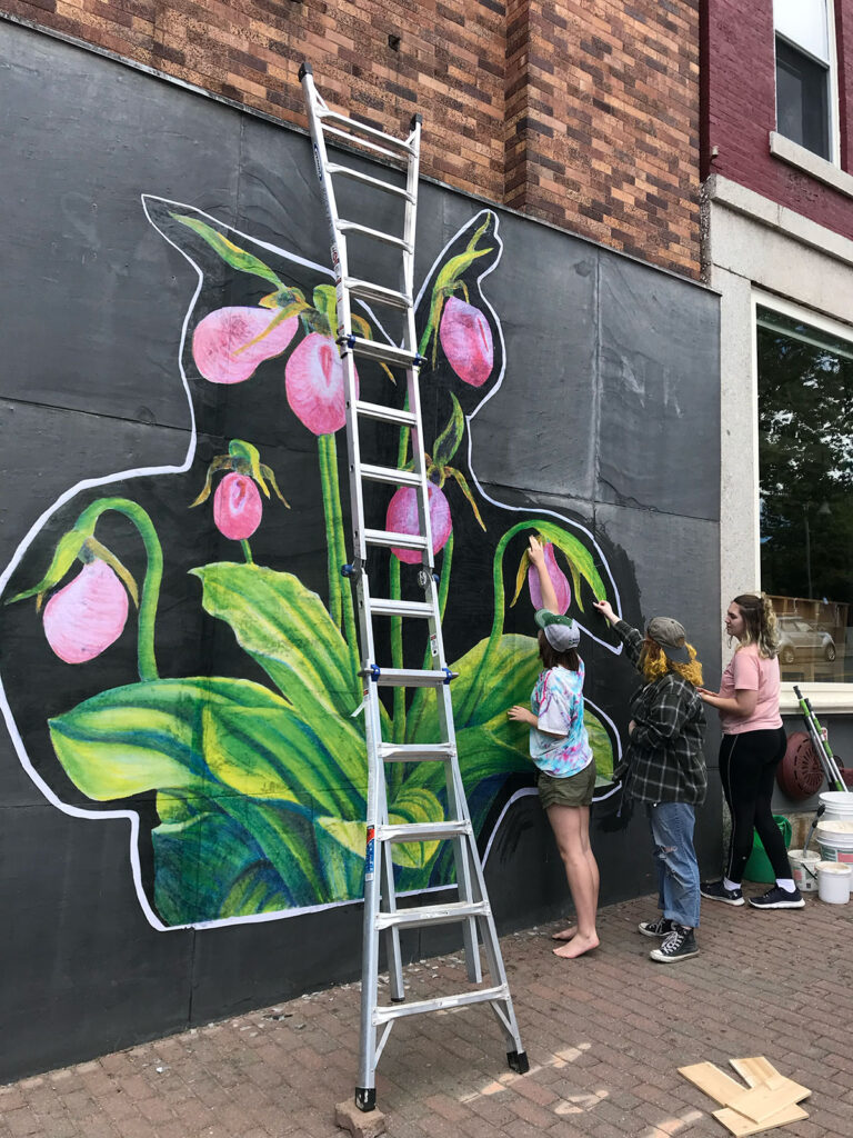 People working on a mural of lady slippers